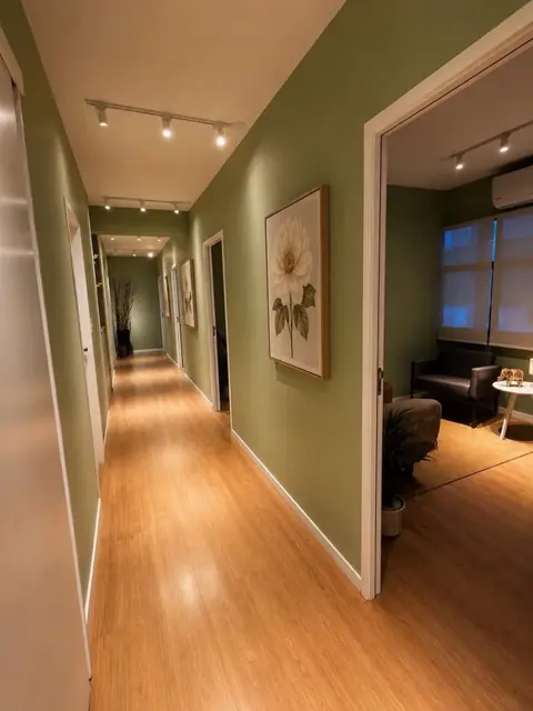 Corredor de piso de madeira com iluminação suave levando às salas de atendimento